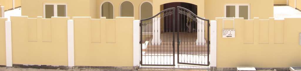 boundry-wall-gallery-5 Yellow boundary wall with white pillars and decorative black iron gate featuring arched design and vertical bars