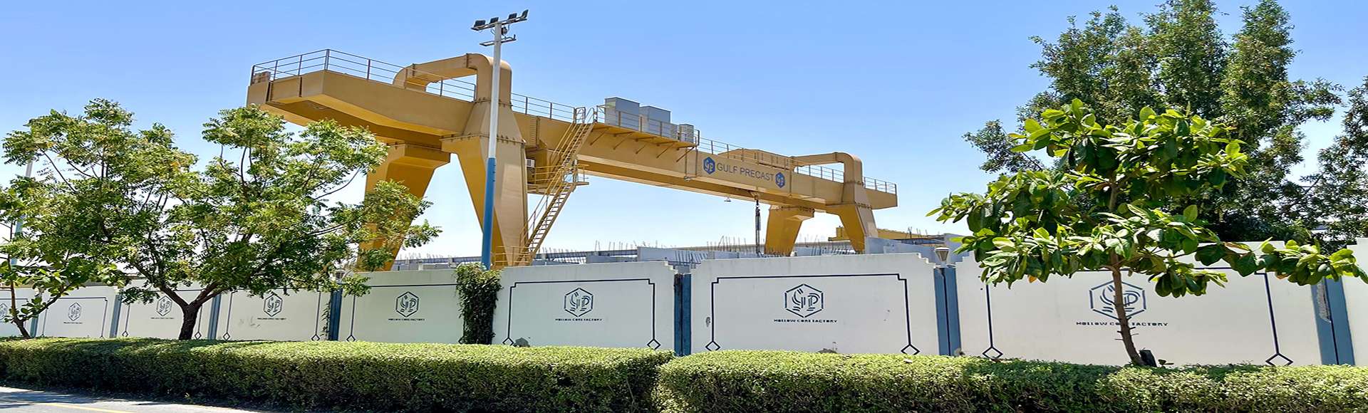 Precast concrete boundary walls with company branding and landscaping at industrial construction site