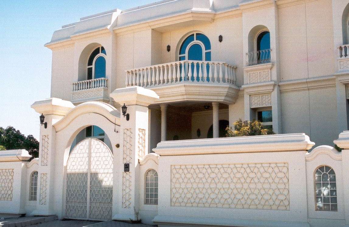 villa_chicos_03 Elegant cream-colored boundary wall with geometric patterns, arched gate, and decorative pillars around luxury villa