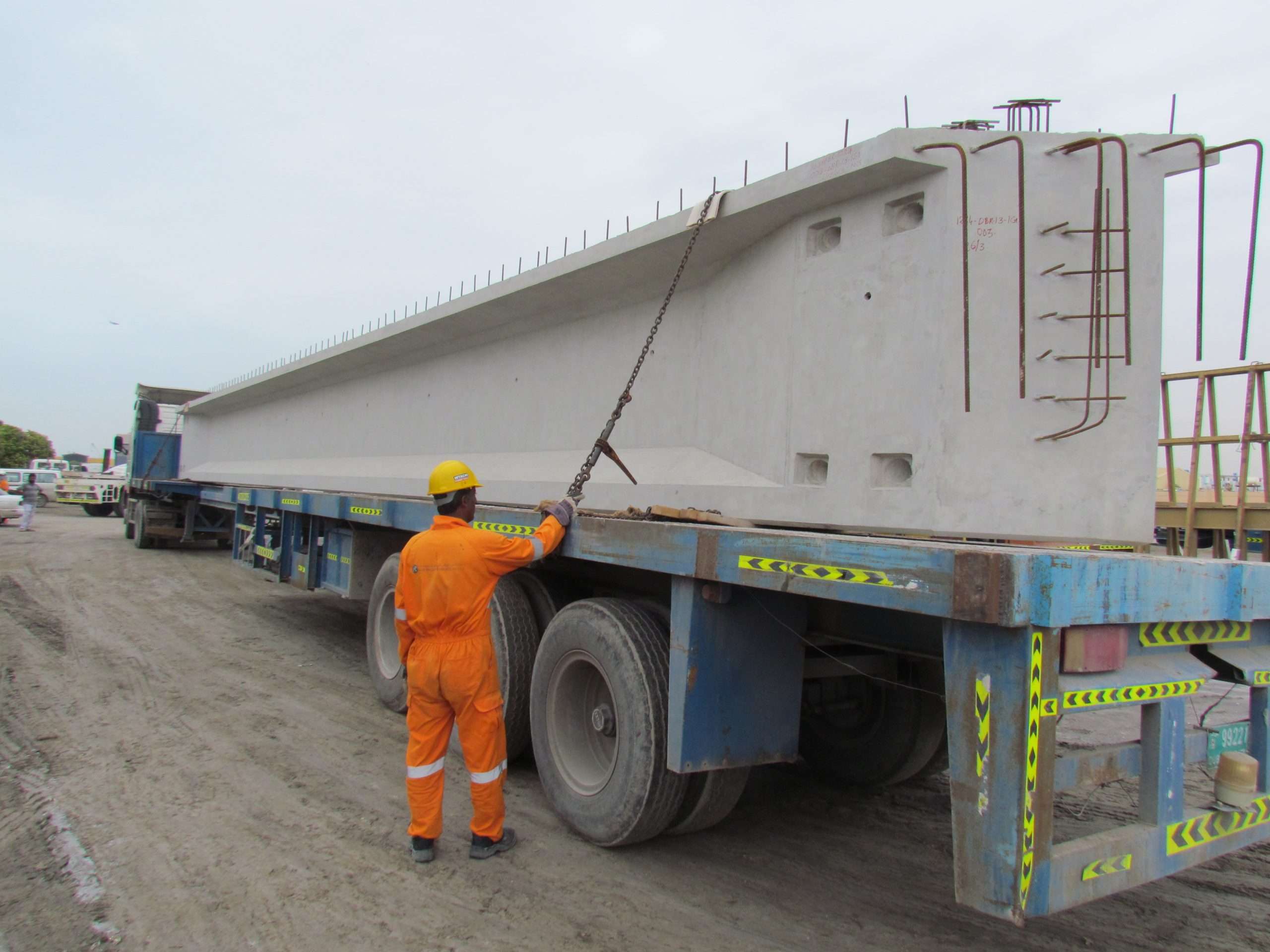 IMG_0007 Worker securing large precast beam on specialized transport truck for construction site delivery